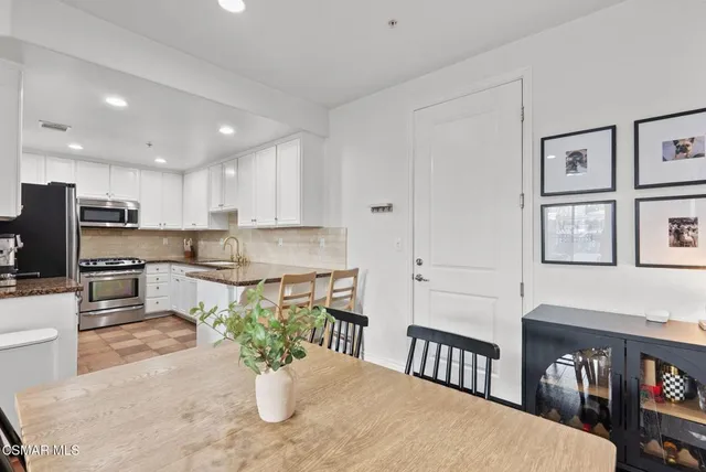 a kitchen with stainless steel appliances kitchen island granite countertop a refrigerator a stove a sink dishwasher and white cabinets with wooden floor