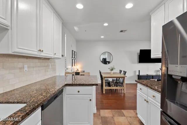 a kitchen with granite countertop a sink and white cabinets