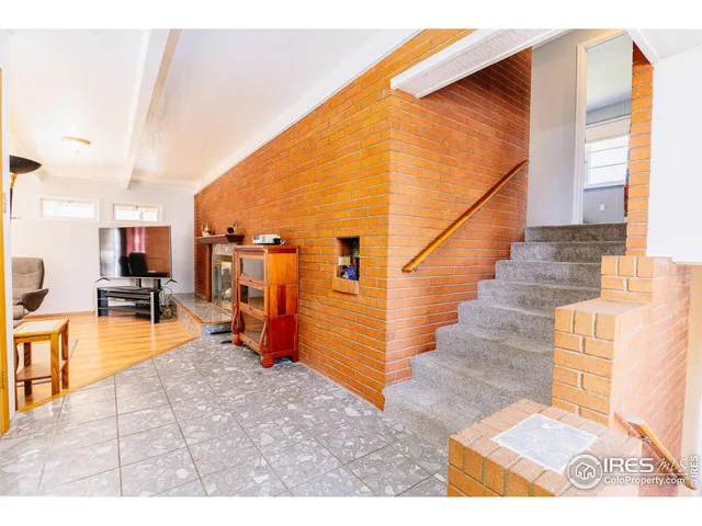 a view of an empty room with window and hardwood floor