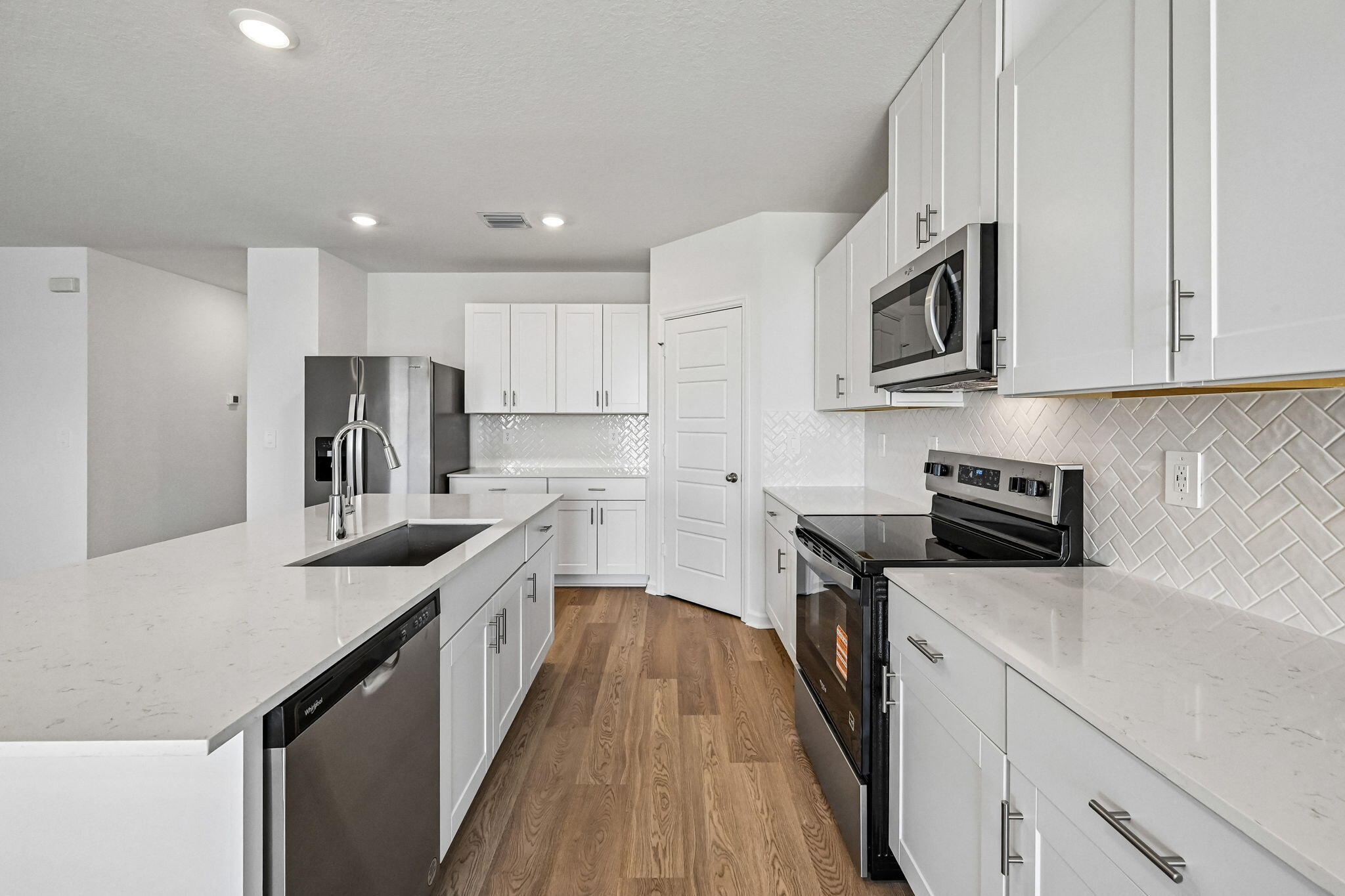 14503 Southwest New Dawn Road Indiantown, FL 34956 - Photo 12 of 42 a kitchen with stainless steel appliances granite countertop a sink a stove top oven a refrigerator white cabinets and wooden floor