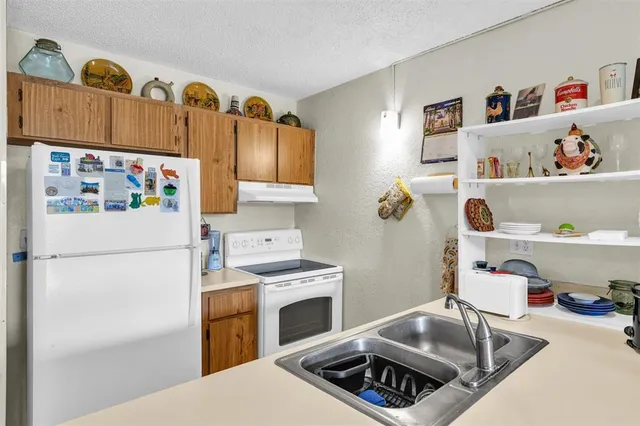 a kitchen with a refrigerator a sink and wooden floor