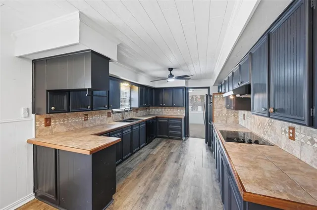a large kitchen with a large counter top a sink stainless steel appliances and cabinets