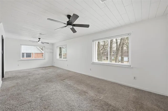 an empty room with wooden floor cabinet and windows