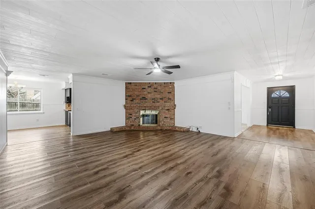 an empty room with wooden floor chandelier and windows