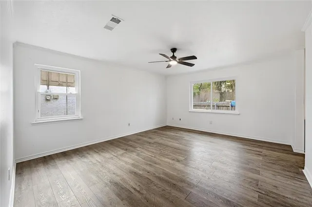 a view of an empty room with a window and wooden floor