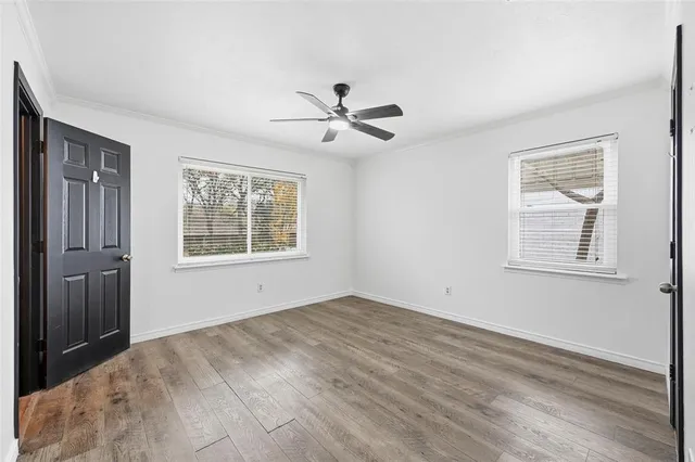 a view of empty room with wooden floor and fan