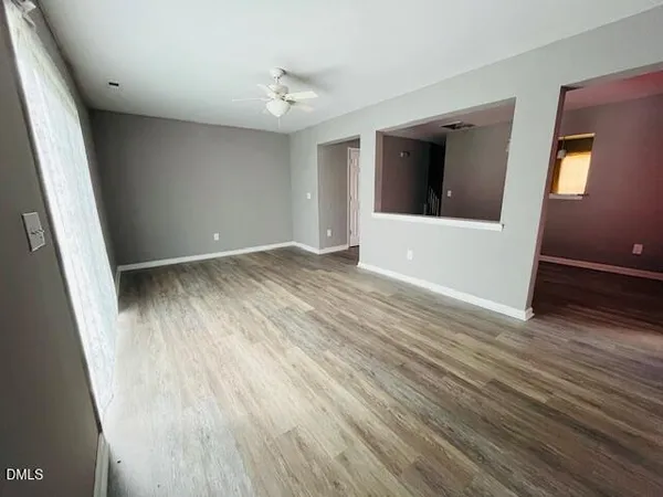 a view of an empty room with wooden floor and a window