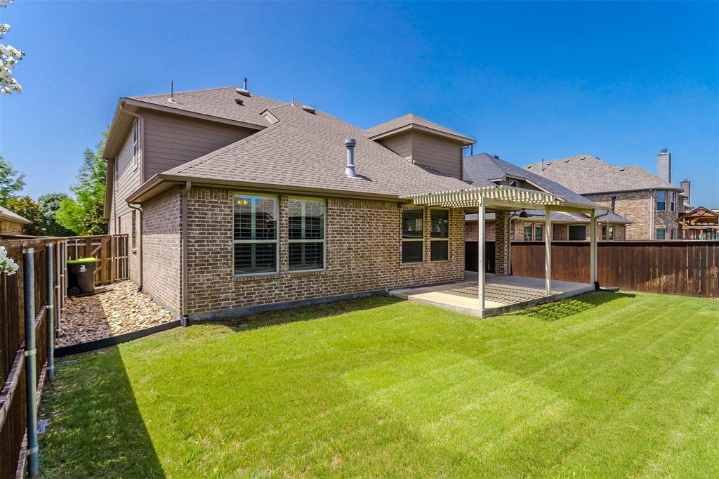 15713 Canyon Ridge Prosper, TX 75078 - Photo 35 of 38 Expansive backyard featuring a manicured lawn, a large covered patio with a ceiling fan, and a perimeter wood fence