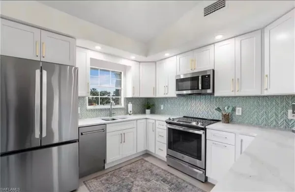a kitchen with white cabinets stainless steel appliances and sink