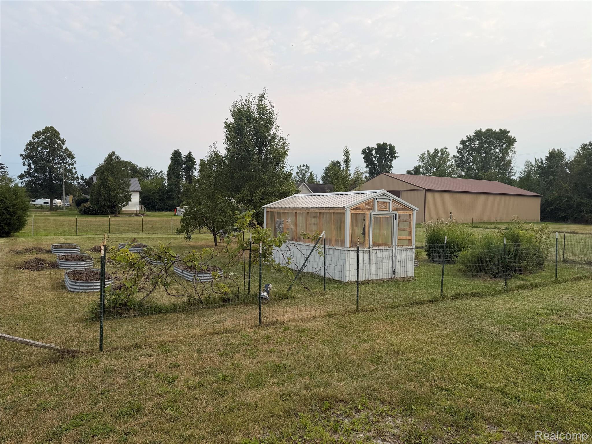 2402 Mertz Road Caro, MI 48723 - Photo 21 of 26 Greenhouse structure, fenced garden area, raised garden beds, and expansive green space