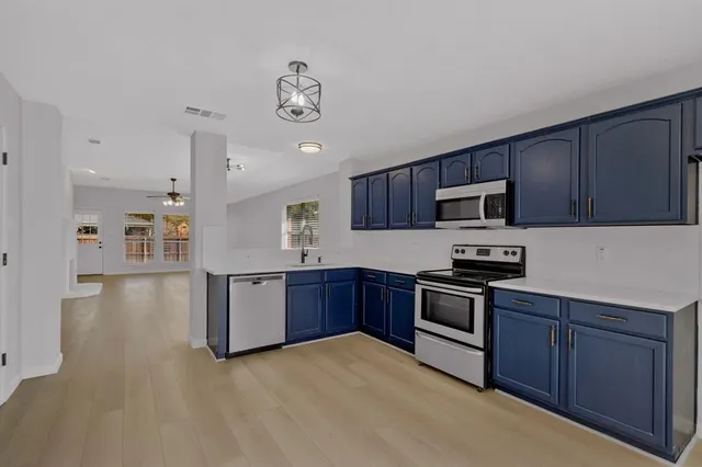 a kitchen with stainless steel appliances granite countertop a stove top oven a sink dishwasher and a refrigerator with wooden floor