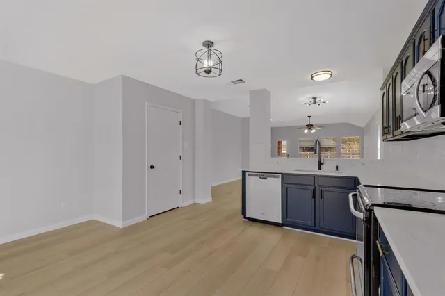 a kitchen with stainless steel appliances granite countertop a sink cabinets and wooden floor