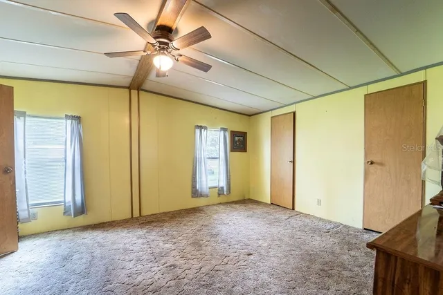 an empty room with closet and a ceiling fan
