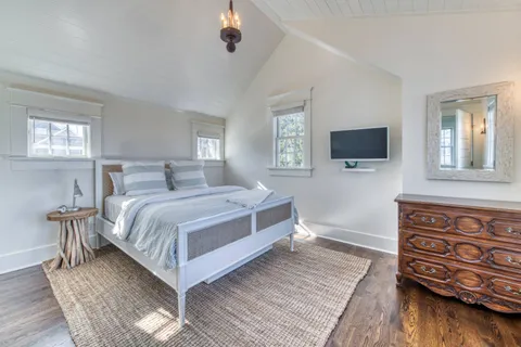 a bedroom with a bed and a flat tv screen on dresser