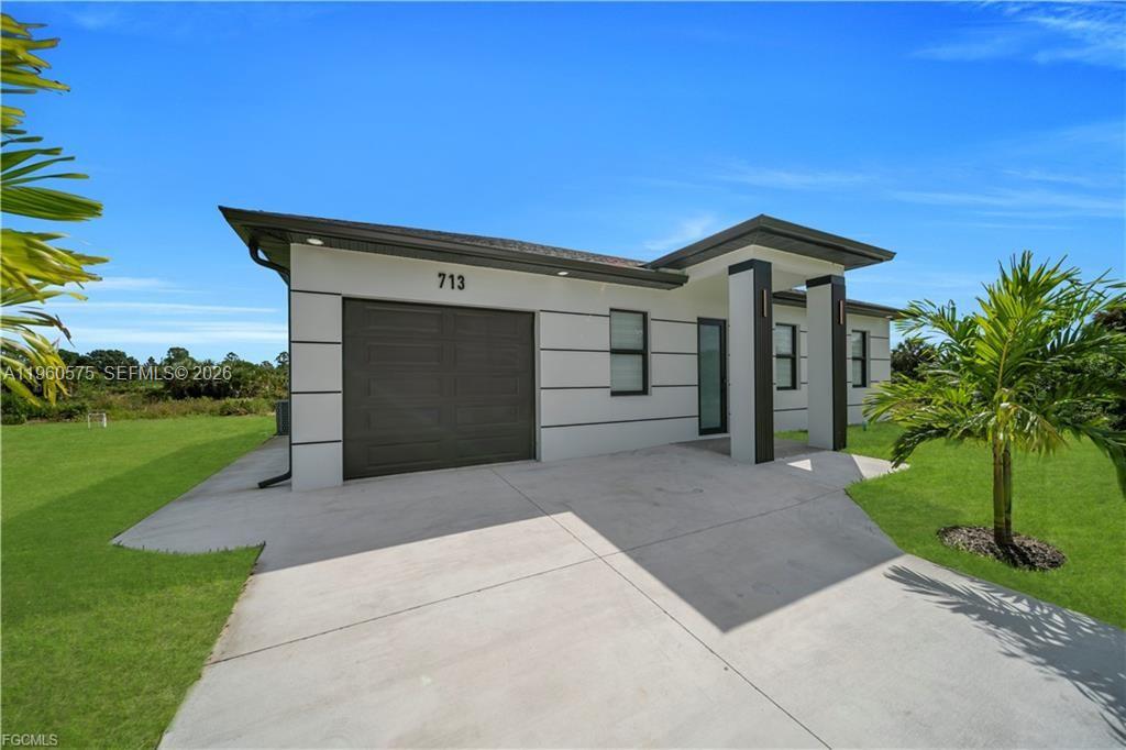 711 Roma Avenue Lehigh Acres, FL 33974 - Photo 1 of 38 a front view of a house with a yard and garage