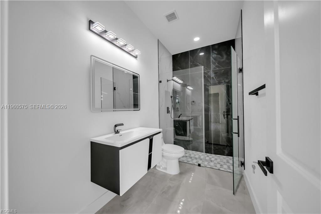 711 Roma Avenue Lehigh Acres, FL 33974 - Photo 21 of 38 a bathroom with a sink mirror toilet shower and vanity