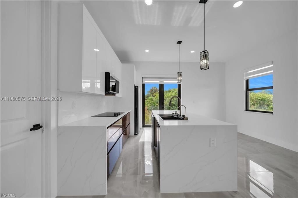 711 Roma Avenue Lehigh Acres, FL 33974 - Photo 10 of 38 a kitchen with stainless steel appliances granite countertop a refrigerator a sink dishwasher a oven a dining table and chairs with wooden floor