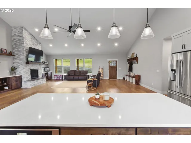a kitchen with stainless steel appliances kitchen island granite countertop a table chairs and a refrigerator