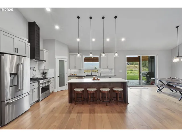 a large kitchen with stainless steel appliances a stove a sink dishwasher and a dining table with the living room view
