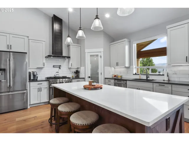 a kitchen with stainless steel appliances granite countertop a refrigerator a stove and a sink