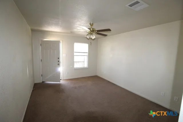 an empty room with windows and fan