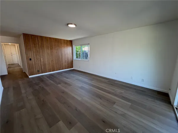 a view of an empty room with wooden floor and window