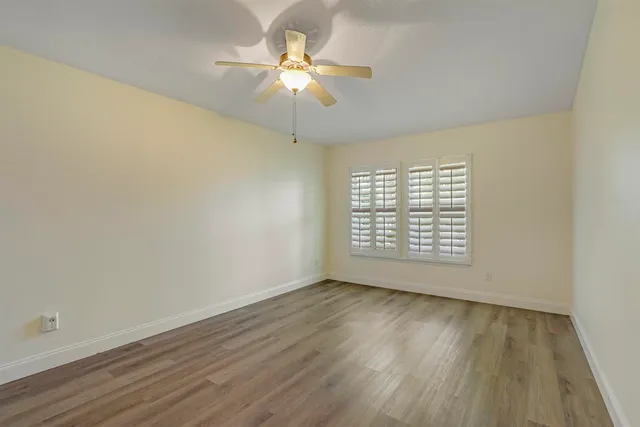 a view of a room with a hardwood floor and a ceiling fan