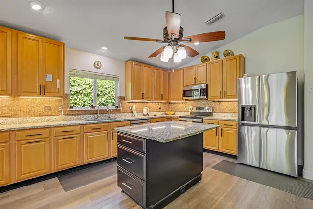 a kitchen with kitchen island granite countertop a stove a sink and refrigerator