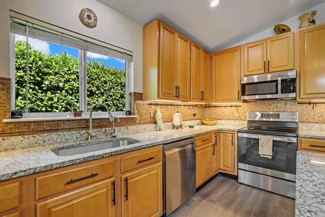 a kitchen with stainless steel appliances granite countertop a sink and a white cabinets