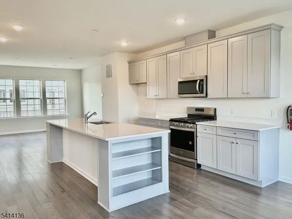 a kitchen with stainless steel appliances white cabinets and a stove top oven