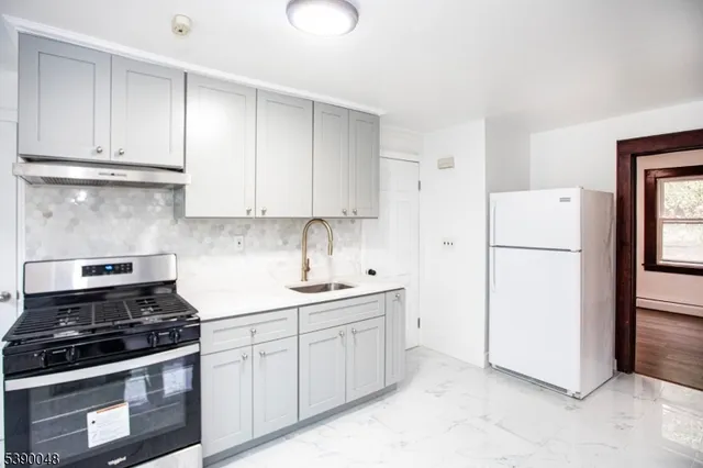 a kitchen with a sink a refrigerator and white cabinets
