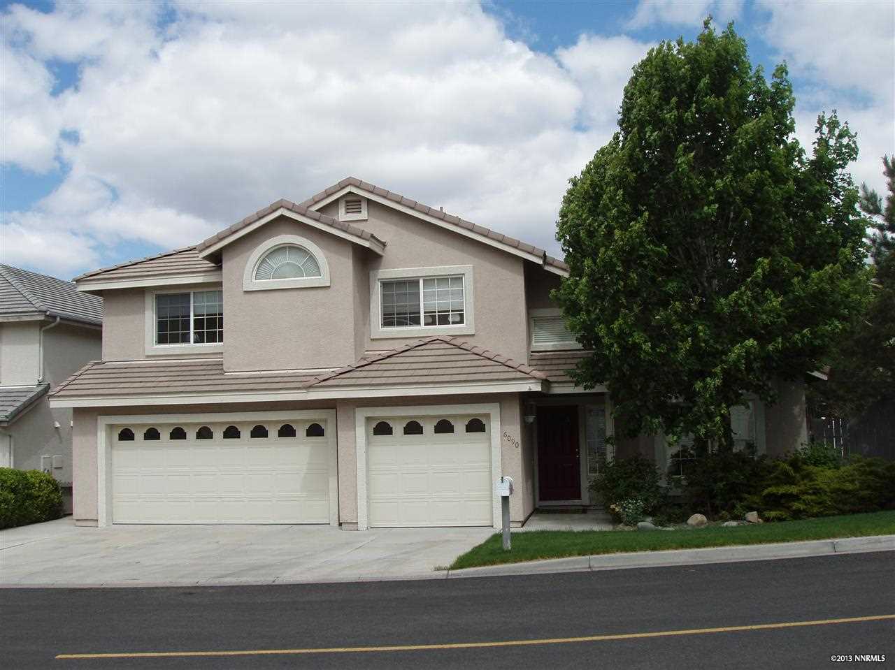 a front view of a house with a garden and trees