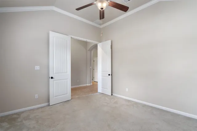 an empty room with a ceiling fan and carpet