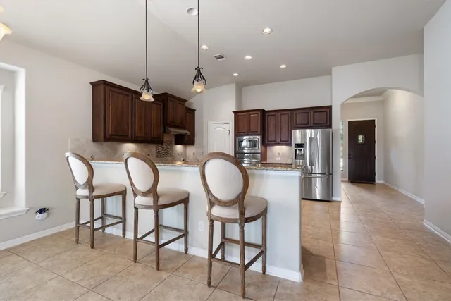 a kitchen with stainless steel appliances granite countertop a refrigerator a oven a sink a island and chairs