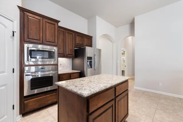 a kitchen with stainless steel appliances granite countertop a refrigerator and a stove top oven