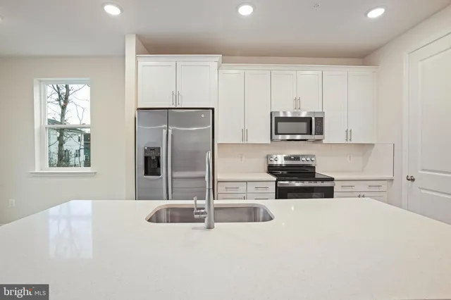 a kitchen with stainless steel appliances a stove a sink a microwave a refrigerator a counter top space and cabinets