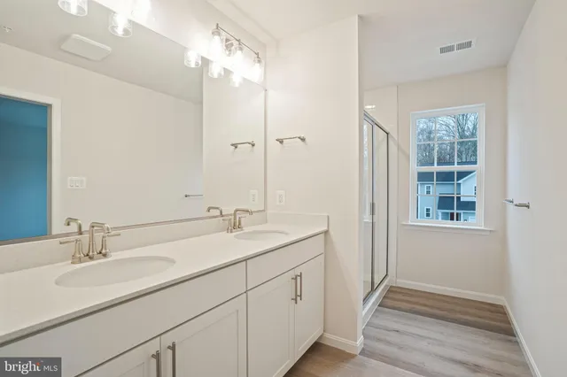 a bathroom with a double vanity sink and mirror with shower