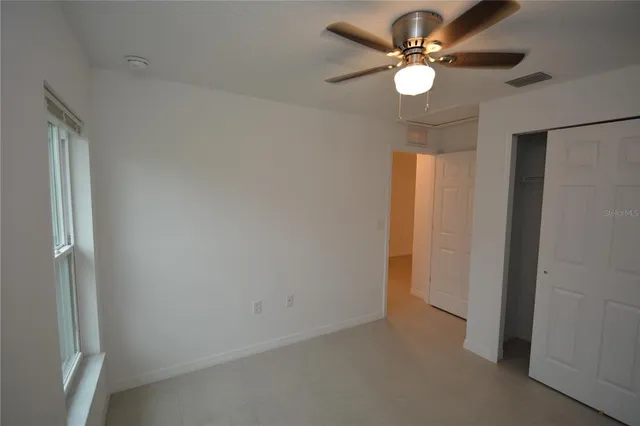 an empty room with a window and a fan