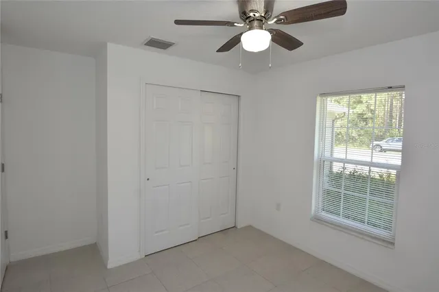 an empty room with windows and fan