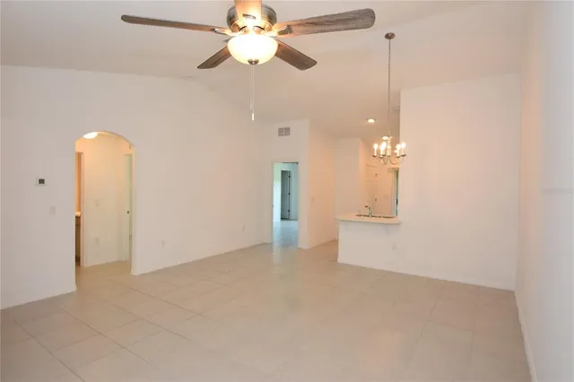 en empty room with fan and a chandelier fan