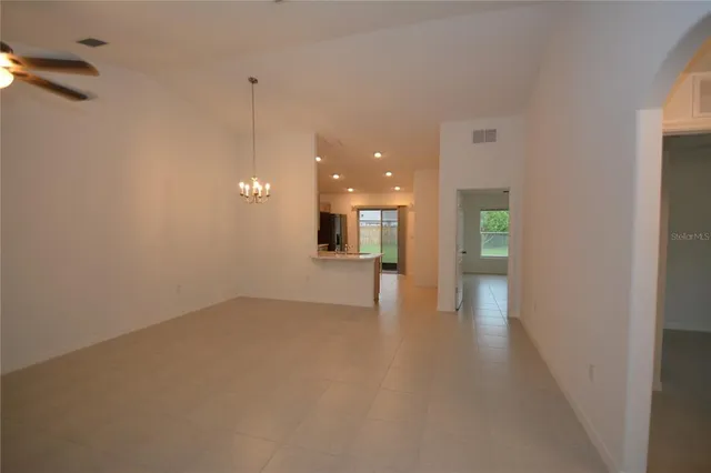 a view of a room with a hanging light and kitchen view