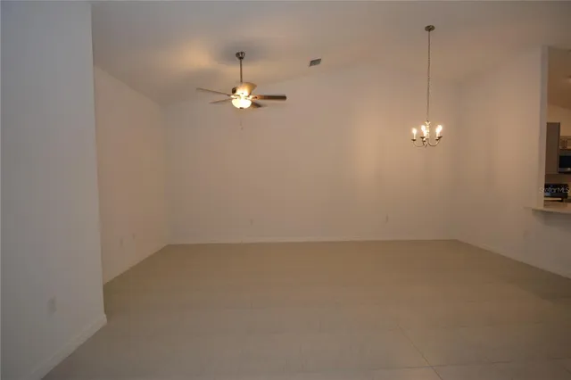 en empty room with chandelier fan and windows