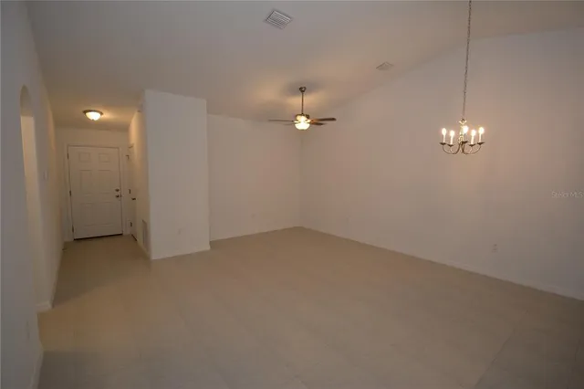 wooden floor in an empty room with a chandelier fan