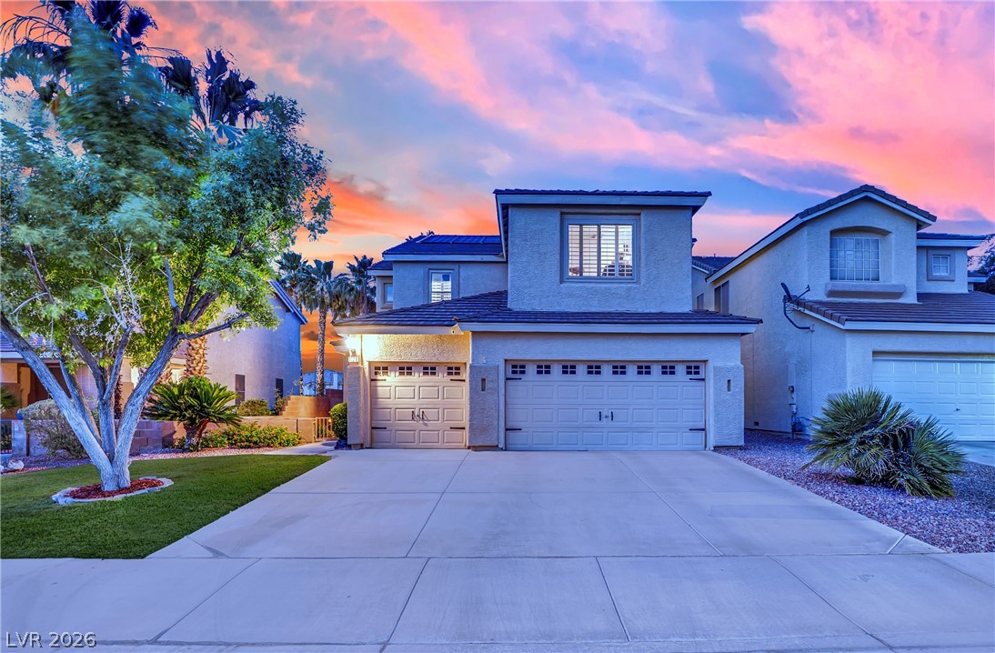 1724 Millstream Way Henderson, NV 89074 - Photo 44 of 60 A well-maintained facade with an inviting driveway, framed by a vibrant sunset.