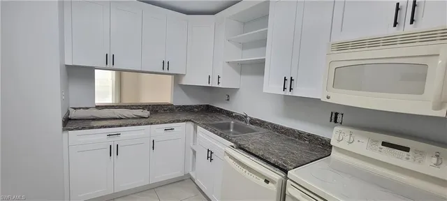 a kitchen with granite countertop a sink a stove and cabinets