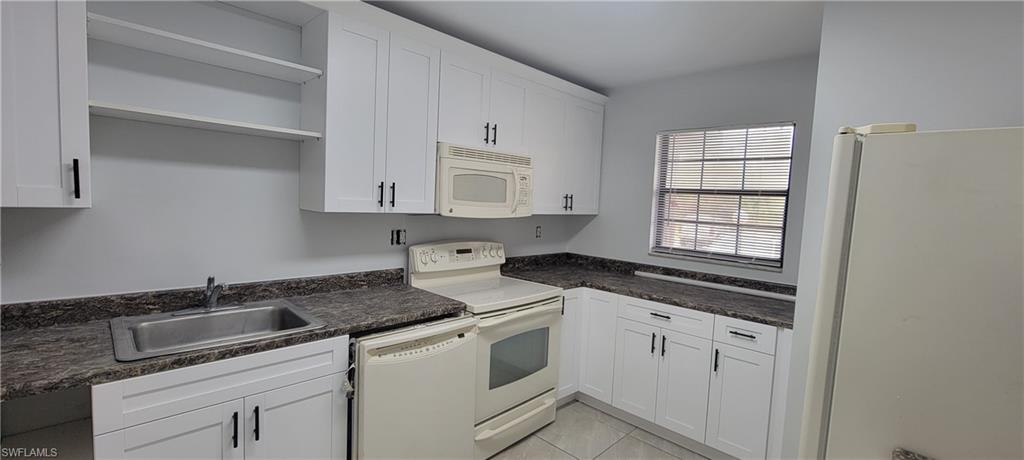 5233 Treetops Drive, Unit Y102 Naples, FL 34113 - Photo 3 of 9 a kitchen with granite countertop white cabinets and white appliances