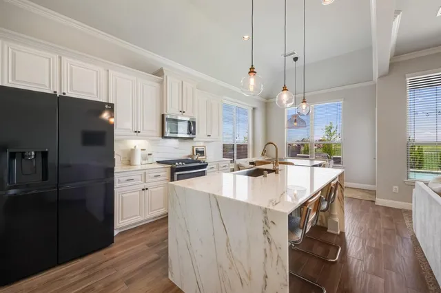 a kitchen with stainless steel appliances a sink a stove a refrigerator cabinets and wooden floor