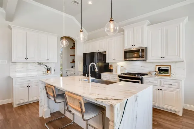 a kitchen with kitchen island granite countertop a stove a sink a center island and cabinets