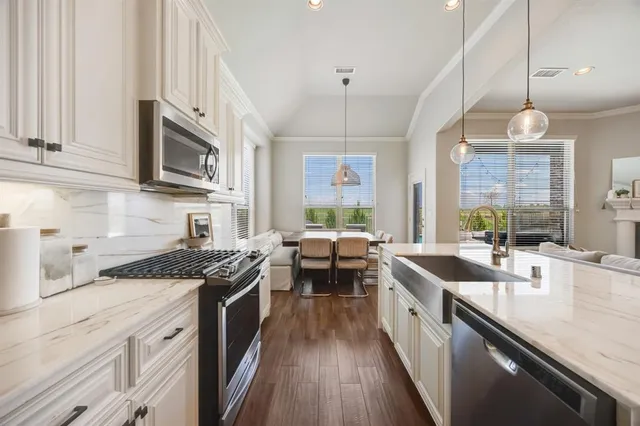 a kitchen with stainless steel appliances granite countertop a sink a stove and a wooden floors