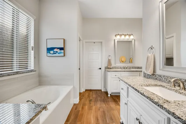 a bathroom with a granite countertop tub sink and mirror